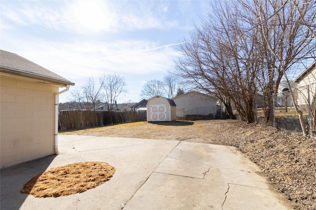 view of patio featuring a storage shed, fence, and an outbuilding