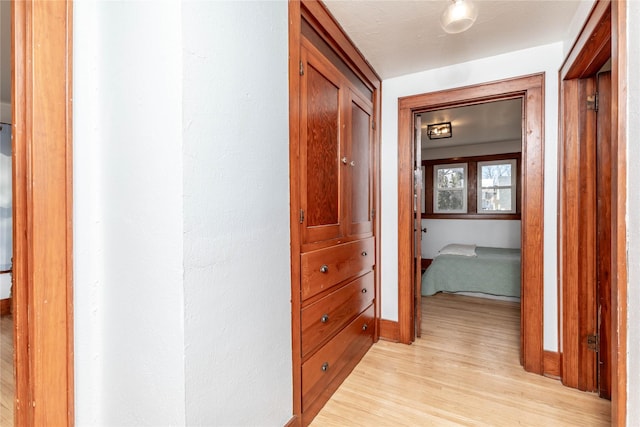 hallway featuring light wood-style floors and baseboards