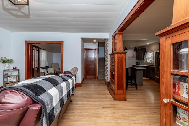 bedroom with light wood finished floors and freestanding refrigerator