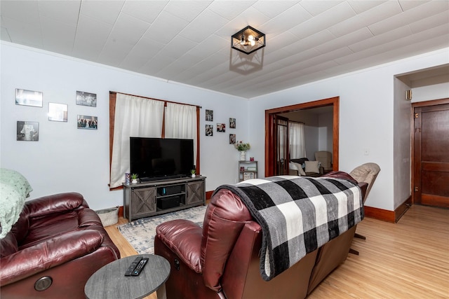 living area featuring light wood finished floors, baseboards, and crown molding