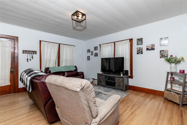 living room featuring ornamental molding, light wood finished floors, and baseboards