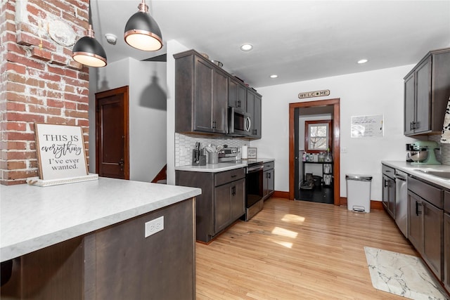 kitchen featuring appliances with stainless steel finishes, light wood-type flooring, dark brown cabinetry, and tasteful backsplash
