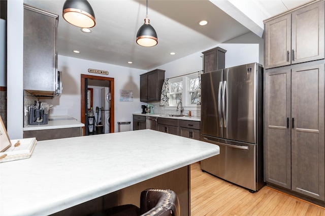 kitchen featuring light wood-type flooring, appliances with stainless steel finishes, light countertops, and a sink