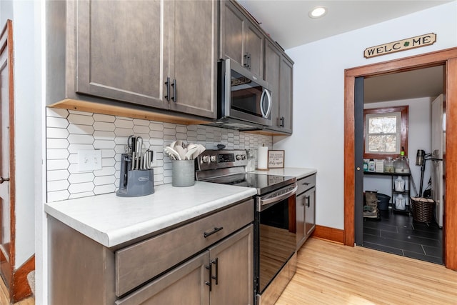 kitchen featuring appliances with stainless steel finishes, light countertops, light wood-style floors, and decorative backsplash