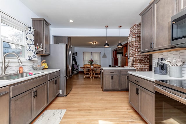 kitchen with stainless steel appliances, light countertops, a sink, and light wood-style flooring