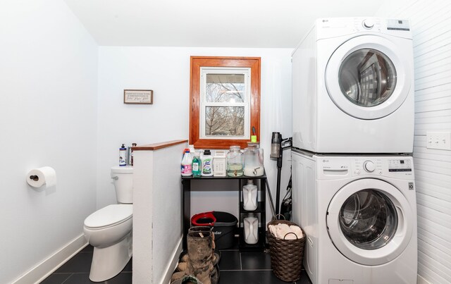 laundry area featuring laundry area, tile patterned flooring, stacked washer and clothes dryer, and baseboards