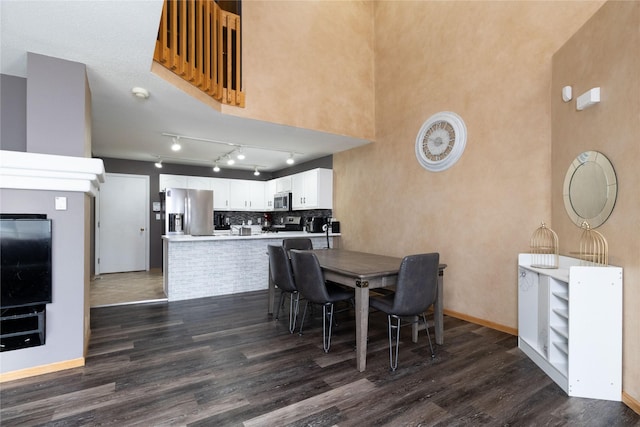 dining space featuring dark wood-style flooring and baseboards