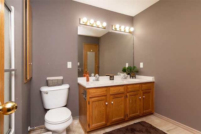 full bathroom featuring baseboards, a sink, toilet, and double vanity