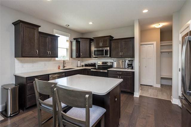 kitchen with dark brown cabinets, appliances with stainless steel finishes, a sink, and dark wood finished floors