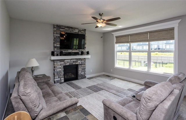 living area featuring a ceiling fan, a fireplace, and baseboards