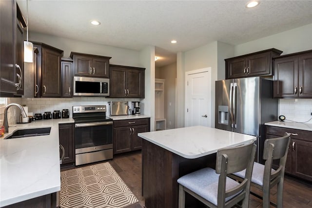 kitchen with dark wood-style floors, appliances with stainless steel finishes, dark brown cabinets, and a sink