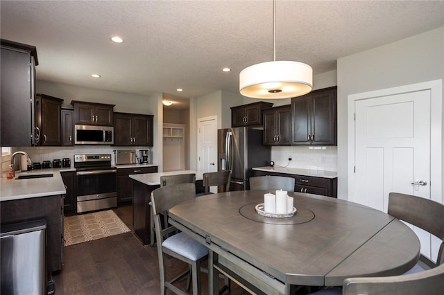 dining area with a textured ceiling, dark wood finished floors, and recessed lighting