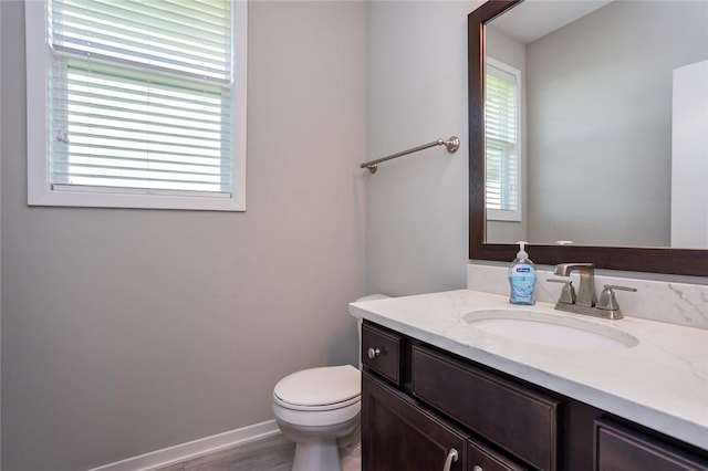 bathroom with toilet, baseboards, and vanity