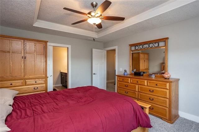 bedroom with baseboards, a raised ceiling, ensuite bath, a textured ceiling, and carpet flooring