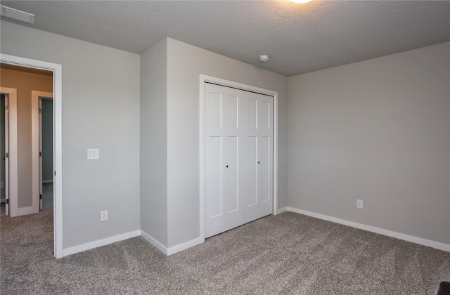 unfurnished bedroom featuring carpet, a closet, visible vents, a textured ceiling, and baseboards