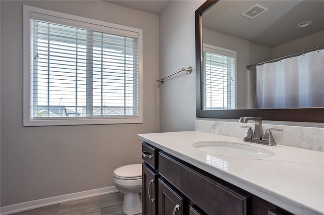 bathroom featuring baseboards, visible vents, toilet, curtained shower, and vanity