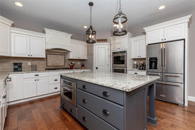 kitchen with custom exhaust hood, white cabinetry, and appliances with stainless steel finishes