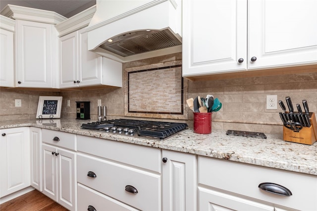 kitchen featuring custom range hood, white cabinets, decorative backsplash, and stainless steel gas stovetop