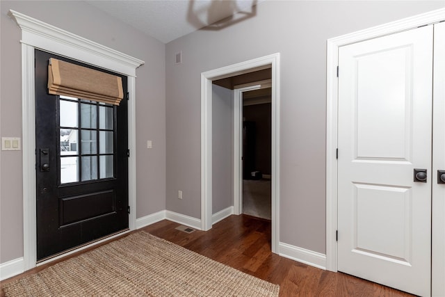 foyer entrance with visible vents, baseboards, and wood finished floors