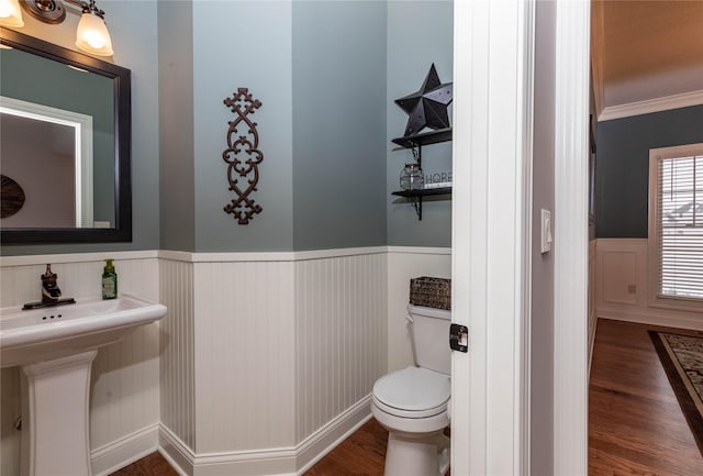 bathroom featuring wainscoting, crown molding, toilet, and wood finished floors