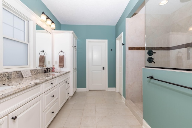 bathroom with double vanity, baseboards, tile patterned floors, walk in shower, and a sink