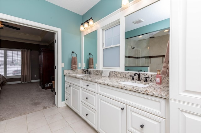 bathroom with double vanity, tiled shower, tile patterned flooring, and a sink