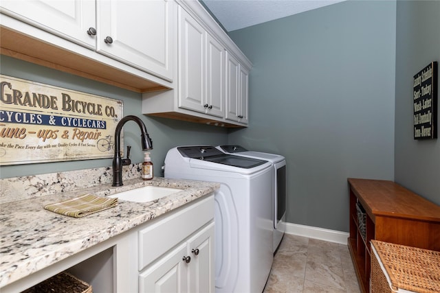 laundry area featuring cabinet space, washing machine and dryer, baseboards, and a sink