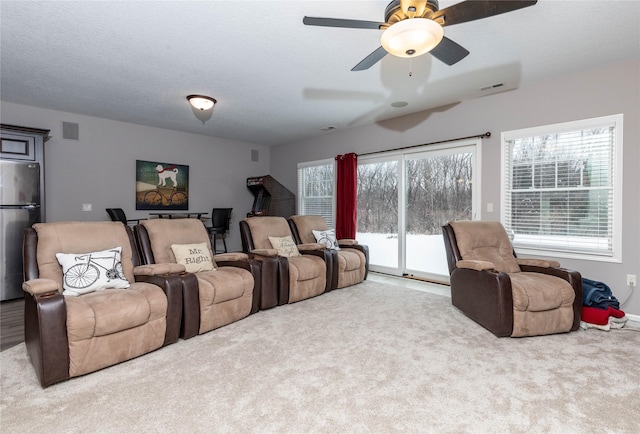 carpeted cinema room featuring a textured ceiling, plenty of natural light, and visible vents