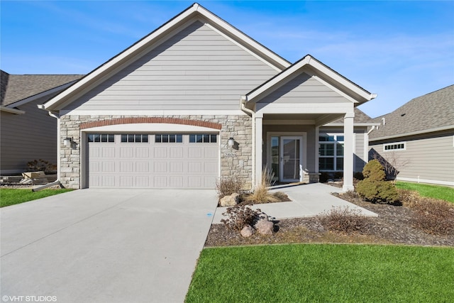 view of front of house featuring stone siding, driveway, and an attached garage