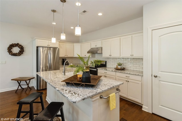 kitchen featuring stainless steel appliances, visible vents, under cabinet range hood, and decorative backsplash