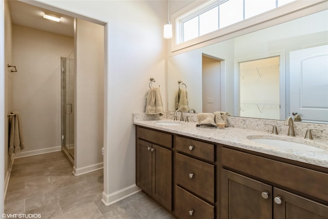 full bath with double vanity, a stall shower, and a sink