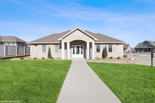 view of front of property with a front yard, roof with shingles, and fence