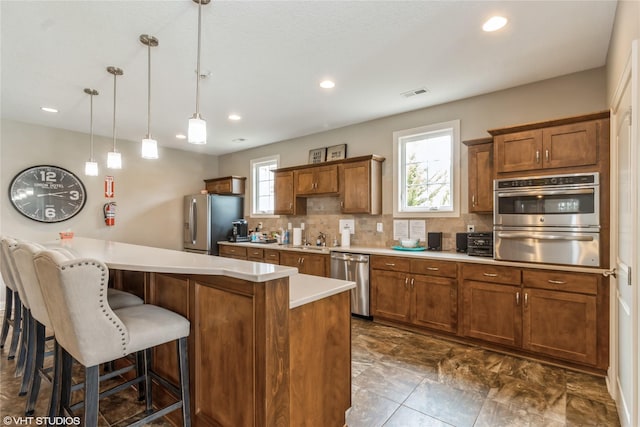 kitchen featuring stainless steel appliances, a breakfast bar, visible vents, and brown cabinets