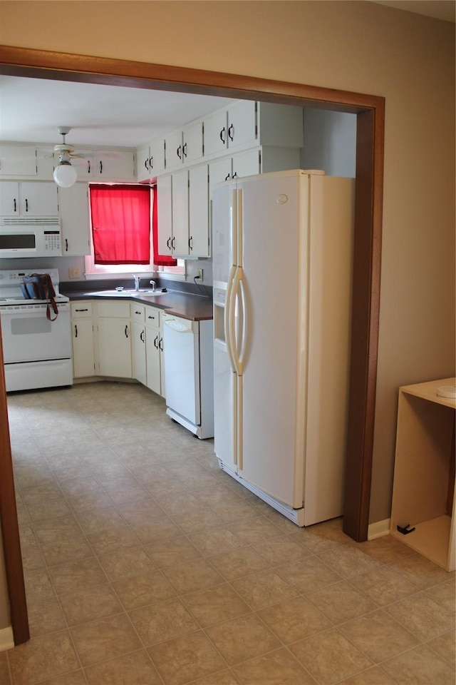 kitchen featuring dark countertops, white appliances, a sink, and a ceiling fan