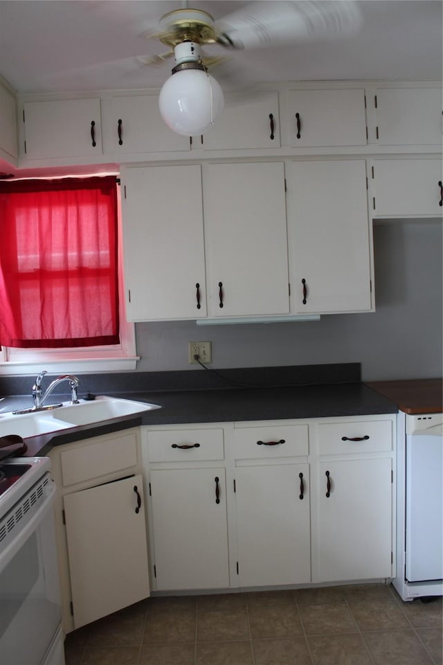 kitchen with dark countertops, white appliances, white cabinets, and a sink