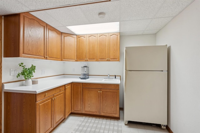 365 Williamson Ct, Pleasant Hill, IA 50327 - kitchen with a sink, brown cabinetry, light countertops, a paneled ceiling, and freestanding refrigerator