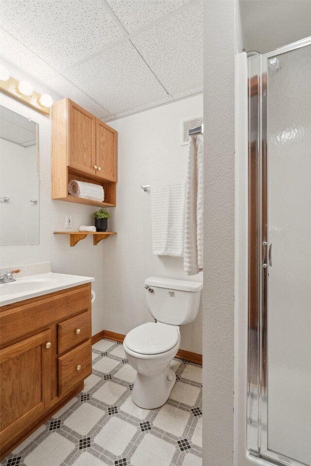 365 Williamson Ct, Pleasant Hill, IA 50327 - bathroom with toilet, vanity, baseboards, a paneled ceiling, and a stall shower