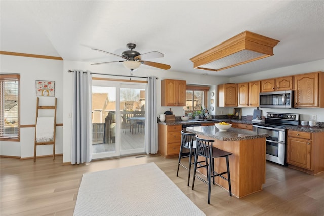 365 Williamson Ct, Pleasant Hill, IA 50327 - kitchen with stainless steel appliances, a center island, a sink, dark countertops, and a kitchen bar