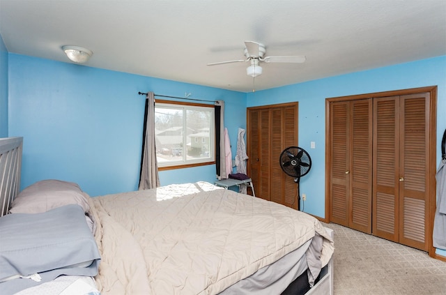 bedroom with light carpet, two closets, and a ceiling fan