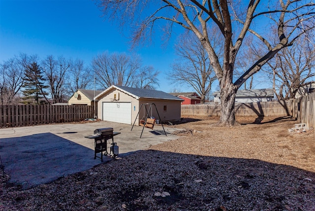 view of yard featuring a fenced backyard, a detached garage, a patio, and an outdoor structure