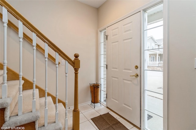 entrance foyer with light tile patterned floors, stairway, and baseboards