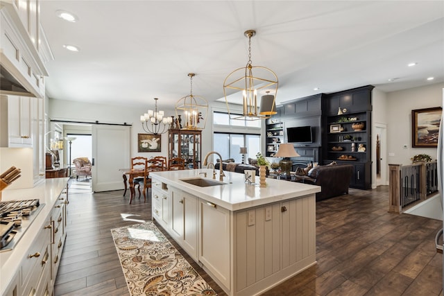 kitchen featuring pendant lighting, dark wood-style flooring, a notable chandelier, a barn door, and a sink