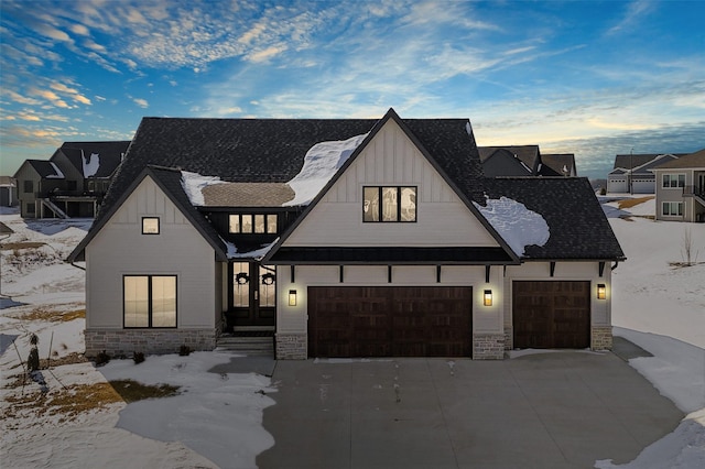 modern farmhouse style home with a garage, driveway, and stone siding