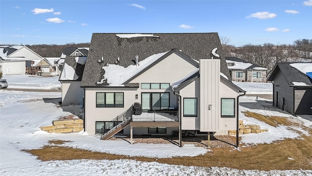 snow covered rear of property with a residential view and stairway