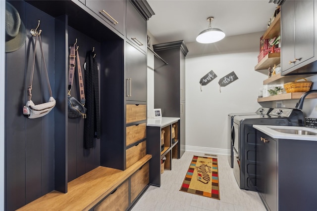 washroom with a sink, cabinet space, baseboards, and washer and dryer