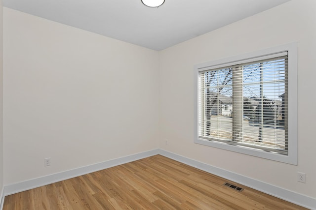 unfurnished room featuring light wood-style floors, visible vents, and baseboards