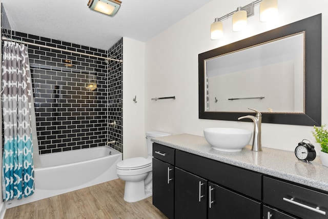 full bathroom featuring shower / bath combination with curtain, toilet, a textured ceiling, vanity, and wood finished floors