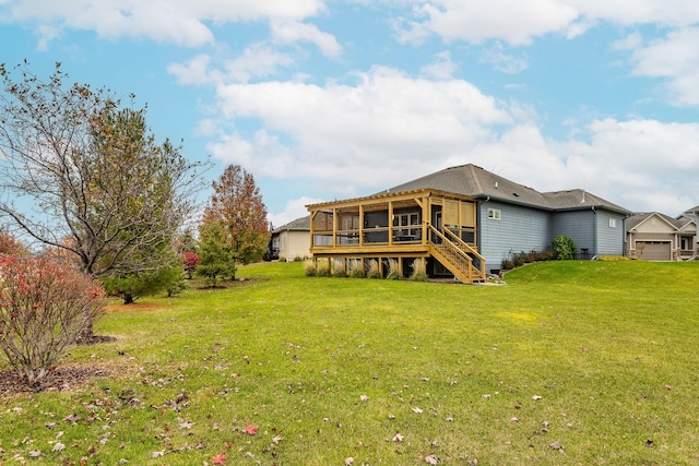 rear view of house featuring a sunroom, a yard, an attached garage, and stairs