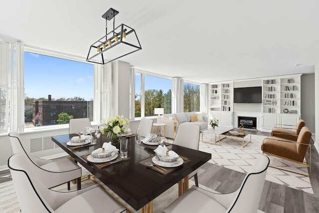 dining space featuring a glass covered fireplace, an inviting chandelier, and wood finished floors