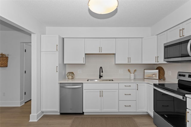 kitchen with decorative backsplash, white cabinets, appliances with stainless steel finishes, light countertops, and a sink